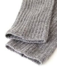 Calentadores de piernas de lana gris con textura suave y acanalada, presentan un diseño abierto en la parte superior e inferior. La tela muestra ligera variación en el tono.