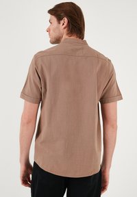 Korte mouwen beige shirt met een gemêleerde stof, button-down kraag en een afgeronde zoom, van achter bekeken.