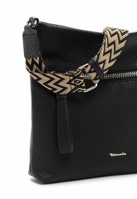 Borsa a mano in pelle nera con superficie testurizzata, dotata di zip diagonale e cinturino regolabile a motivo zigzag in nero e tan.