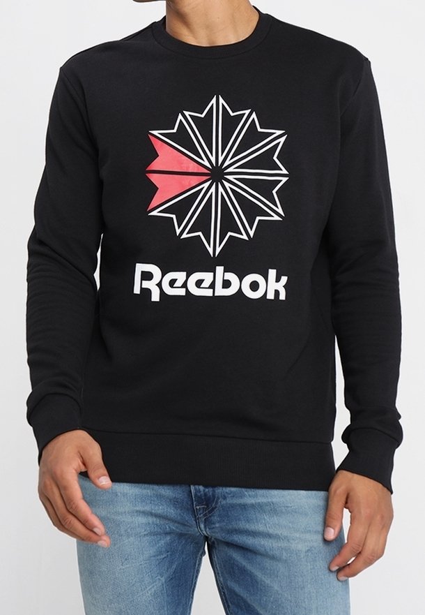 Svart sweatshirt med en geometrisk stjärngrafik i vitt och rött, med "Reebok"-logotyp i fet vit text, tillverkad av en bomullsblandning.