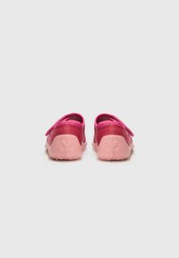 Pink children's shoes with a smooth upper, elastic strap, and textured pink sole featuring a floral pattern on the bottom.