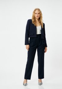 Navy stripe-taittinen lyhyt bleiseri, valkoinen hihaton paita, räätälöidyt tummansiniset housut, metallinhohtoiset hopeakorkokengät. Sileä kangas ja siistit linjat läpi.