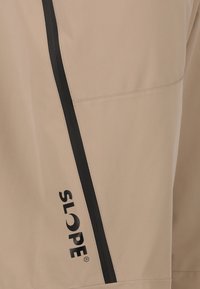 Beiger Stoff mit schwarzem diagonalen Streifen und schwarzem Text "SLOPE", der vertikal nahe dem Streifen gedruckt ist.
