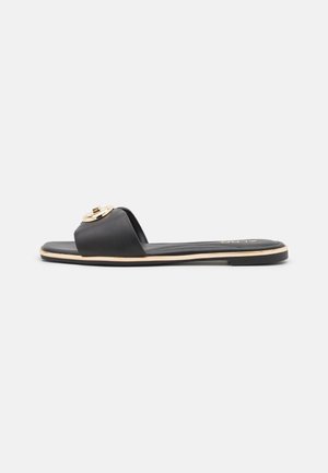 Schwarze flache Slide-Sandale mit breitem Riemen, goldfarbener runder Schnalle und schmalem goldfarbenen Rand entlang der Sohlenkanten.