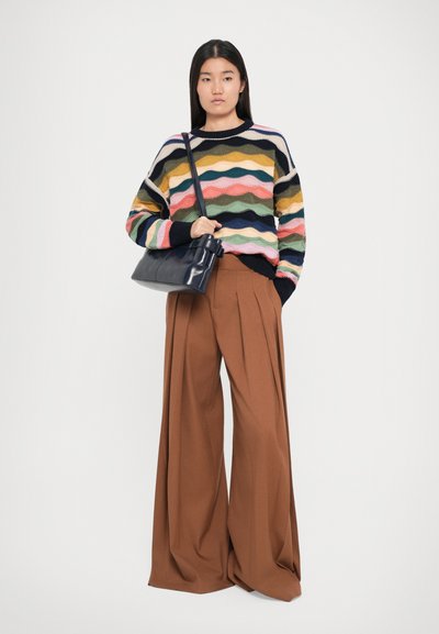 Gebreide pullover in een meerkleurig golfpatroon; gecombineerd met bruin, hoog-wijd broek; met een zwarte handtas.