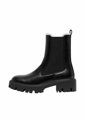 Black ankle-high boot with chunky treaded sole, elastic side panels, pull tab, and white fleece lining, shown in left side profile.