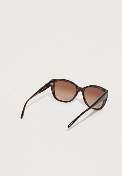 Τετράγωνα γυαλιά ηλίου με καφέ φακούς με διαβάθμιση και λεπτούς βραχίονες, τοποθετημένα πάνω σε λευκή επιφάνεια.