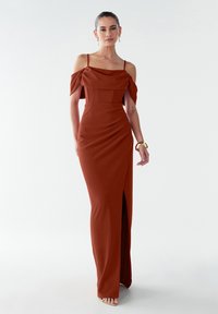 Langes, schulterfreies Abendkleid in verbranntem Orange mit einem strukturierten Oberteil, drapierten Details und einem hohen Schlitz bis zum Oberschenkel. Glatte Textur.