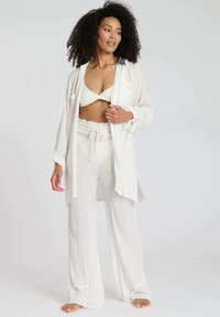 Set da salotto bianco in tre pezzi composto da un kimono trasparente a maniche lunghe, un top corto e pantaloni a gamba larga con una fantasia a righe testurizzata.