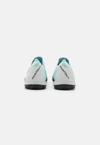Des crampons de football bleu clair avec des semelles noires, dotés d'un dessus texturé, d'accents orange contrastants et de la marque "PHANTOM GT" sur le talon.