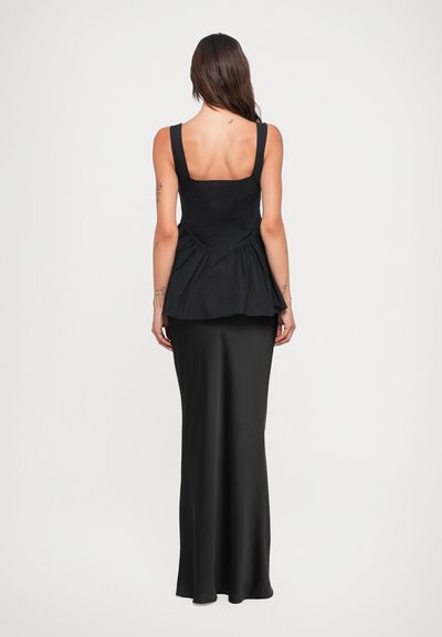 Black peplum top with square neckline, paired with a fitted, long black skirt. Smooth texture with a flowing silhouette. Minimalist design.