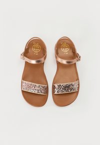 Rosa gull sandaler med en blank finish, med en bred glitrende stropp, en brun såle og en justerbar ankelstropp.