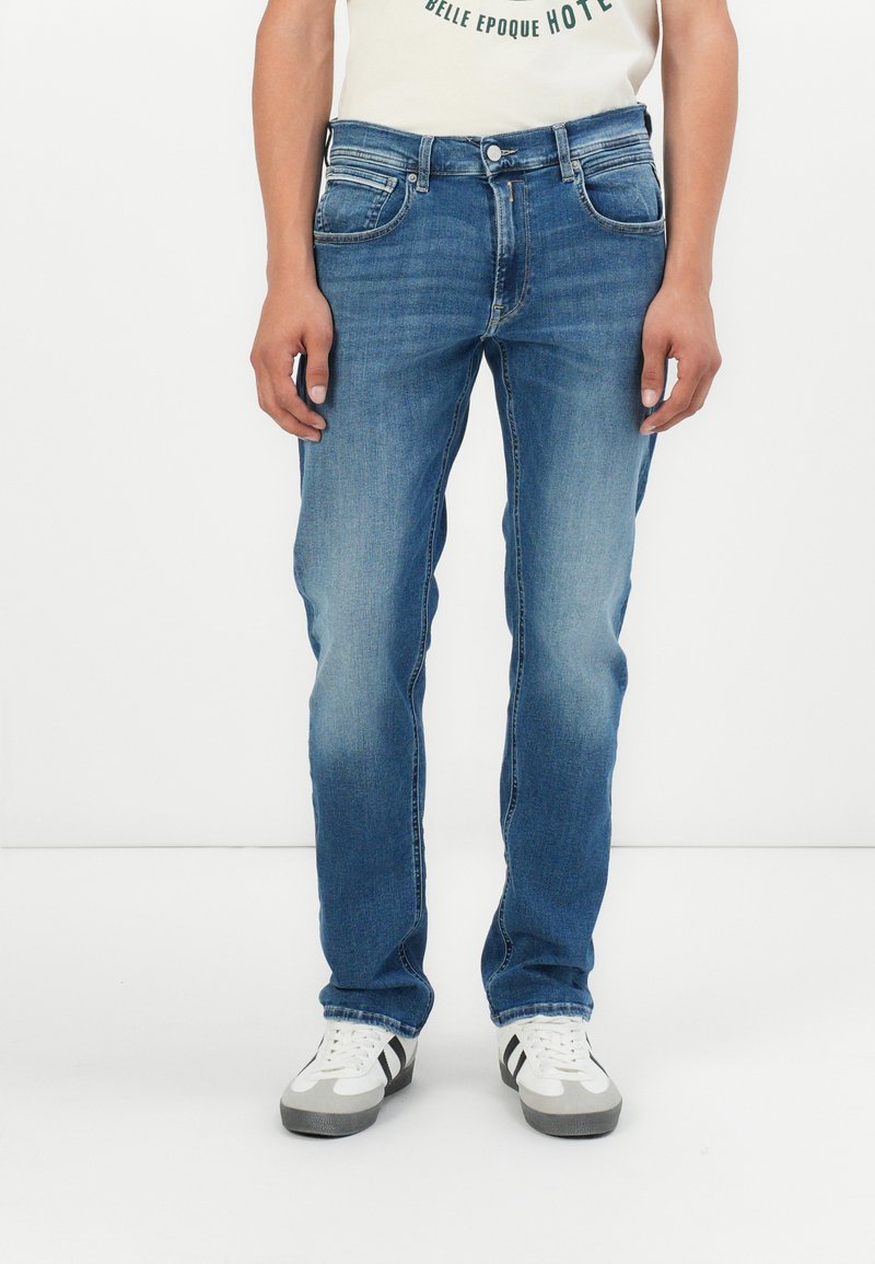 Jeans din denim albastru cu o croială dreaptă, cinci buzunare și un efect subtil de decolorare. Asortați cu adidași albi cu dungi negre.