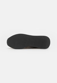 Black rubber outsole with deep horizontal grooves for traction; rounded shape transitioning from a thicker heel to a thinner forefoot.