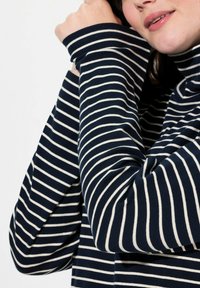 Mörkblå och vit randig polotröja med långa ärmar, tillverkad av ett mjukt material. Har en avslappnad passform och uppvikta muddarmar.