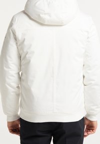 Witte gewatteerde jas met capuchon, met een gladde textuur, elastische manchetten en een strak ontwerp. Achteraanzicht toont een eenvoudige naaddetail.