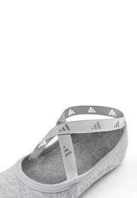 Gray slip-on shoe with soft textile upper, round toe, and gray elastic straps featuring a logo pattern. Textured sole for grip.