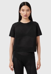 Zwarte cropped top met een geribbelde textuur, korte mouwen en een ronde halslijn. Gecombineerd met een bijpassende geribbelde onderkant.