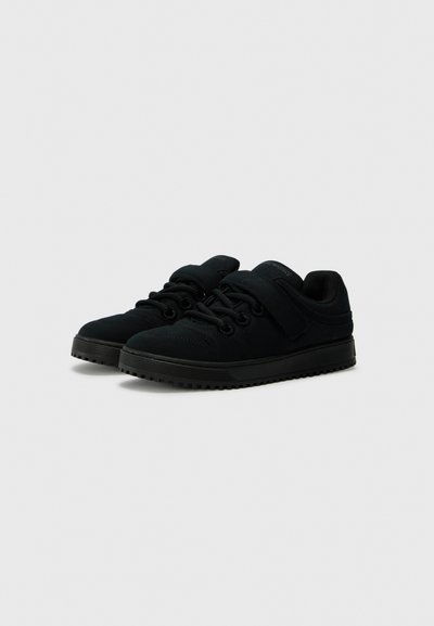 Black athletic shoes with a suede and mesh upper, featuring a padded collar, elastic laces, and a hook-and-loop strap. Textured rubber sole.