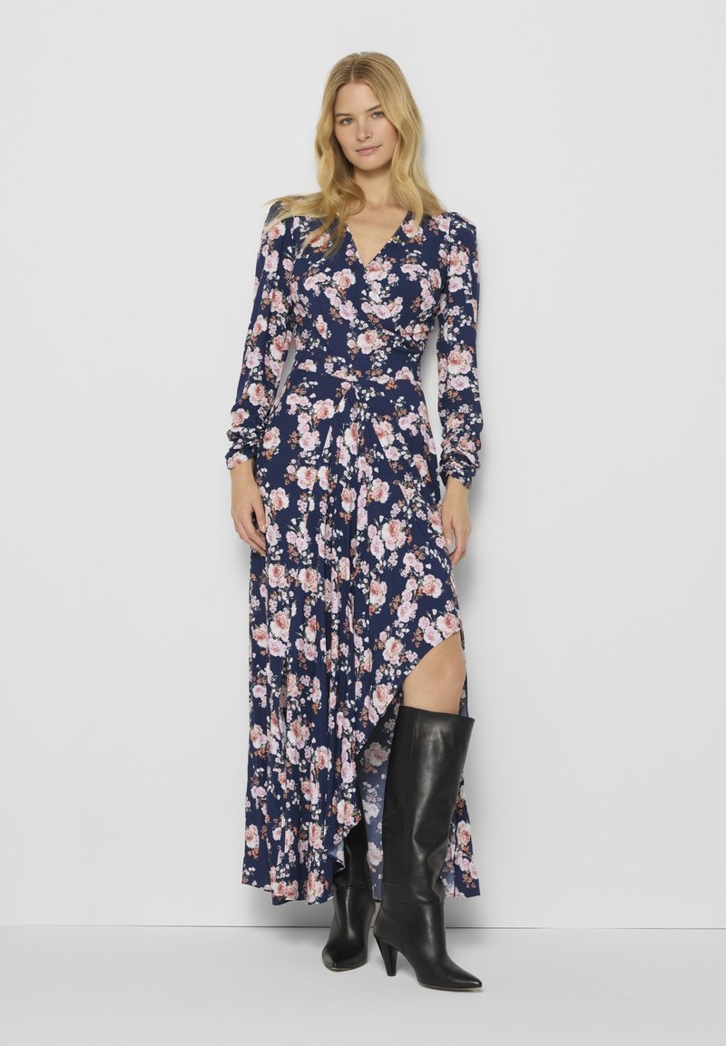 Maxi sukienka w granatowym kolorze z różowym kwiatowym wzorem, z długimi rękawami, fasonem kopertowym i wysokim rozcięciem. W zestawieniu z czarnymi botkami do kolan.