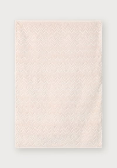Toalha de um tom rosa claro com um padrão texturizado em zigzag e uma superfície macia e peluda. As bordas estão bem acabadas. Adequada para uso em banho.