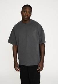 Mørkegrå oversized t-shirt lavet af blødt bomuld. Har en rund halsudskæring, korte ærmer og en afslappet pasform. Minimale syninger.