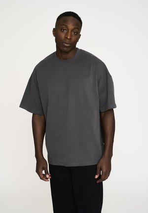 Mørkegrå oversized t-shirt lavet af blødt bomuld. Har en rund halsudskæring, korte ærmer og en afslappet pasform. Minimale syninger.