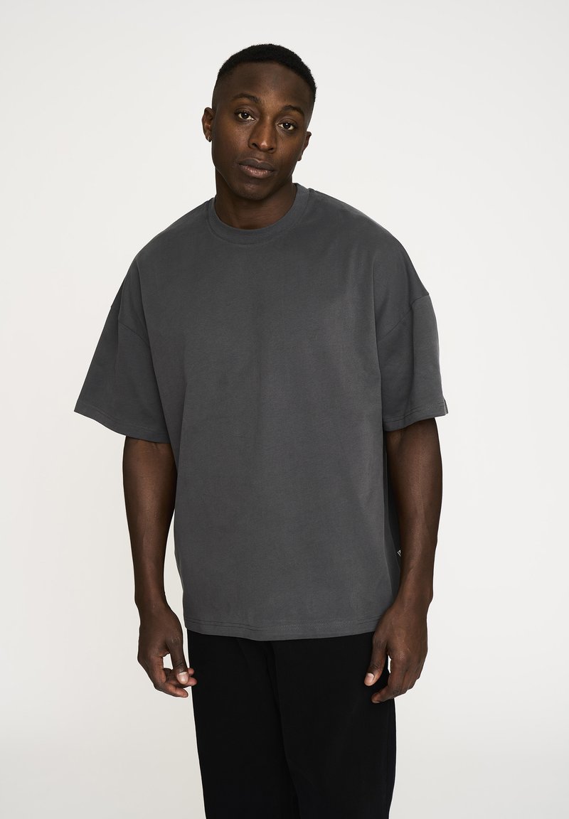 Mørkegrå oversized t-shirt lavet af blødt bomuld. Har en rund halsudskæring, korte ærmer og en afslappet pasform. Minimale syninger.