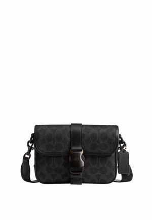 Sac bandoulière noir avec une texture subtilement imprimée, fermeture à boucle à l'avant, bandoulière réglable et une étiquette suspendue sur le côté.