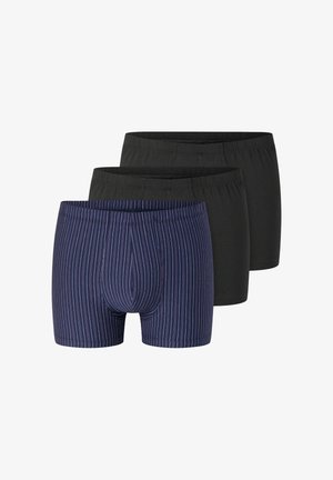 Tres pares de calzoncillos tipo bóxer para hombre, dos de color negro sólido y uno azul marino con finas rayas verticales rojas y blancas, dispuestos superpuestos sobre un fondo blanco.