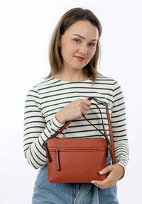 Borsa a tracolla rossa in pelle con scomparto principale con zip e tasca esterna. Texture liscia, forma rettangolare, tracolla regolabile.