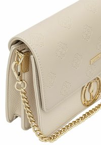 Kremowa skórzana torebka z wytłaczanym wzorem, złotymi akcentami i łańcuszkowym paskiem. Teksturowane dno z płaskim, usztywnionym fasonem.