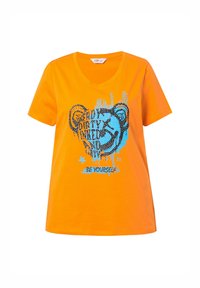 Orange bomulds T-shirt med v-udskæring, der har et grafisk design i blå og sort, der viser en bjørn og tekst elementer. Korte ærmer.