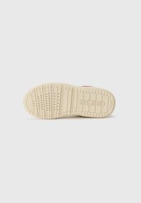 Semelle en caoutchouc blanche pour baskets avec une surface texturée, présentant des rainures pour une meilleure adhérence et le logo "Geox" embossé sur le côté.