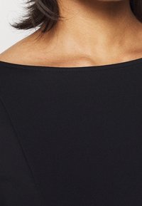Schwarzes, tailliertes Kleid mit glatter Textur und schulterfreier Ausschnittkante, das über saubere Nähte und ein maßgeschneidertes Design verfügt.