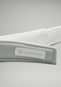 Čelenka Lululemon v světle šedé textilii s žebrovanou strukturou, měkkým bílým vnitřkem a bílou nášivkou s logem na straně.