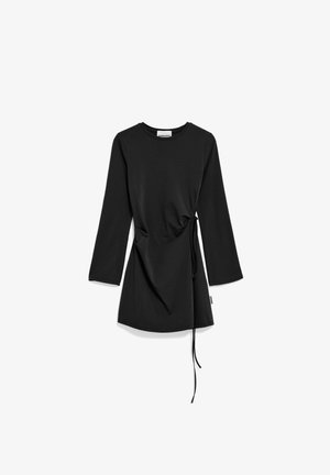 Zwarte lange mouwen jurk met ronde halslijn en verstelbare zijstrik die een geplooid effect creëert op een witte achtergrond.