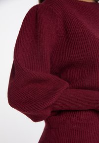 Burgundy bordázott kötött pulóver, amely pufi ujjakkal, textúrált anyaggal és szűkített derékpánttal rendelkezik.