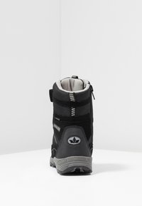 Botte noire imperméable avec un tissu texturé et une semelle en caoutchouc. Présente une fermeture éclair, des accents gris et un logo au talon.