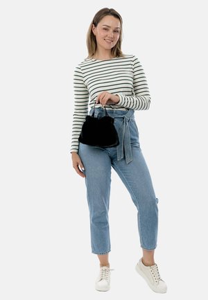 Borsa in finta pelliccia nera con forma arrotondata e manici corti, abbinata a una camicia a righe a maniche lunghe e jeans blu a vita alta.