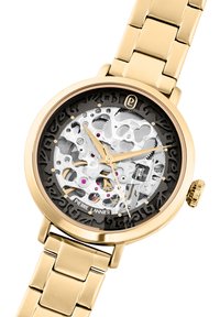 Orologio in tono oro con quadrante scheletrato trasparente, che rivela il movimento argentato e accenti rosa. Presenta un bracciale in metallo a maglie e una corona.