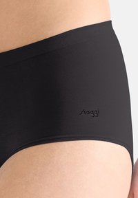Svarta Sloggi-trosor med ett glatt, elastiskt tyg. Hög midja med subtil logotypdetalj nära midjebandet. Mjuk känsla och sömlösa kanter.