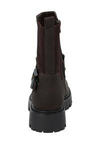 Botas de tobillo marrones con un material suave y un panel de tela texturizada, suela negra gruesa y cierre de cremallera en el lateral.