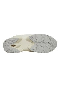 Suola di una sneaker con una suola in gomma testurizzata dal motivo a zigzag, principalmente di colore crema con accenti grigio chiaro.