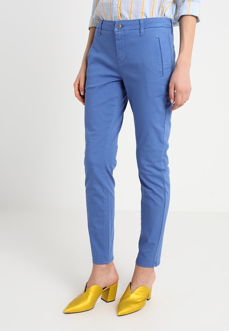 Světle modré, úzké kalhoty z bavlny, s jednou přední kapsou a zipem v pase. Spárováno se žlutými vyššími mules.