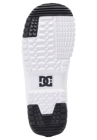Semelle de chaussure de skate en noir et blanc avec une surface texturée, présentant un logo DC au centre et différents motifs de traction pour l'adhérence.