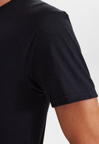 Sort bomuld T-shirt med rund hals og korte ærmer. Stof har en glat tekstur og en tætsiddende pasform med minimale sømme.