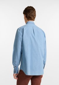 Lichtblauwe long-sleeve shirt gemaakt van zachte stof, met een puntige kraag, knoopmanchetten en een split aan de achterkant.