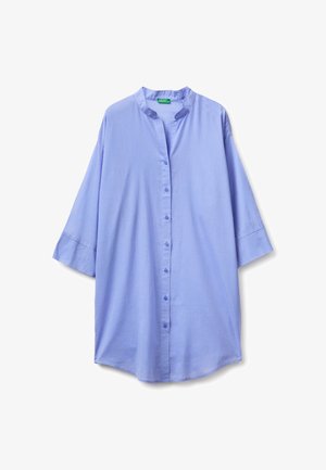 Chemise oversize bleu clair à boutons avec manches longues et encolure sans col, présentée à plat sur fond blanc.
