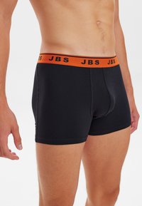 Zwarte stretch katoenen boxershorts met een oranje tailleband waarop de tekst "JBS" in zwart staat. Slank design zonder zichtbare patronen.